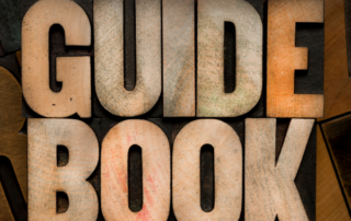 Untitled design 18 | McCormick Insurance Wooden letter blocks spell GUIDE BOOK on a textured stacked background with warm tones