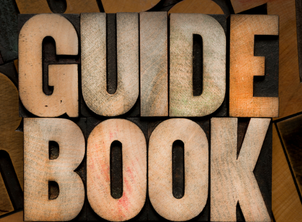 Untitled design 18 | McCormick Insurance Wooden letter blocks spell GUIDE BOOK on a textured stacked background with warm tones